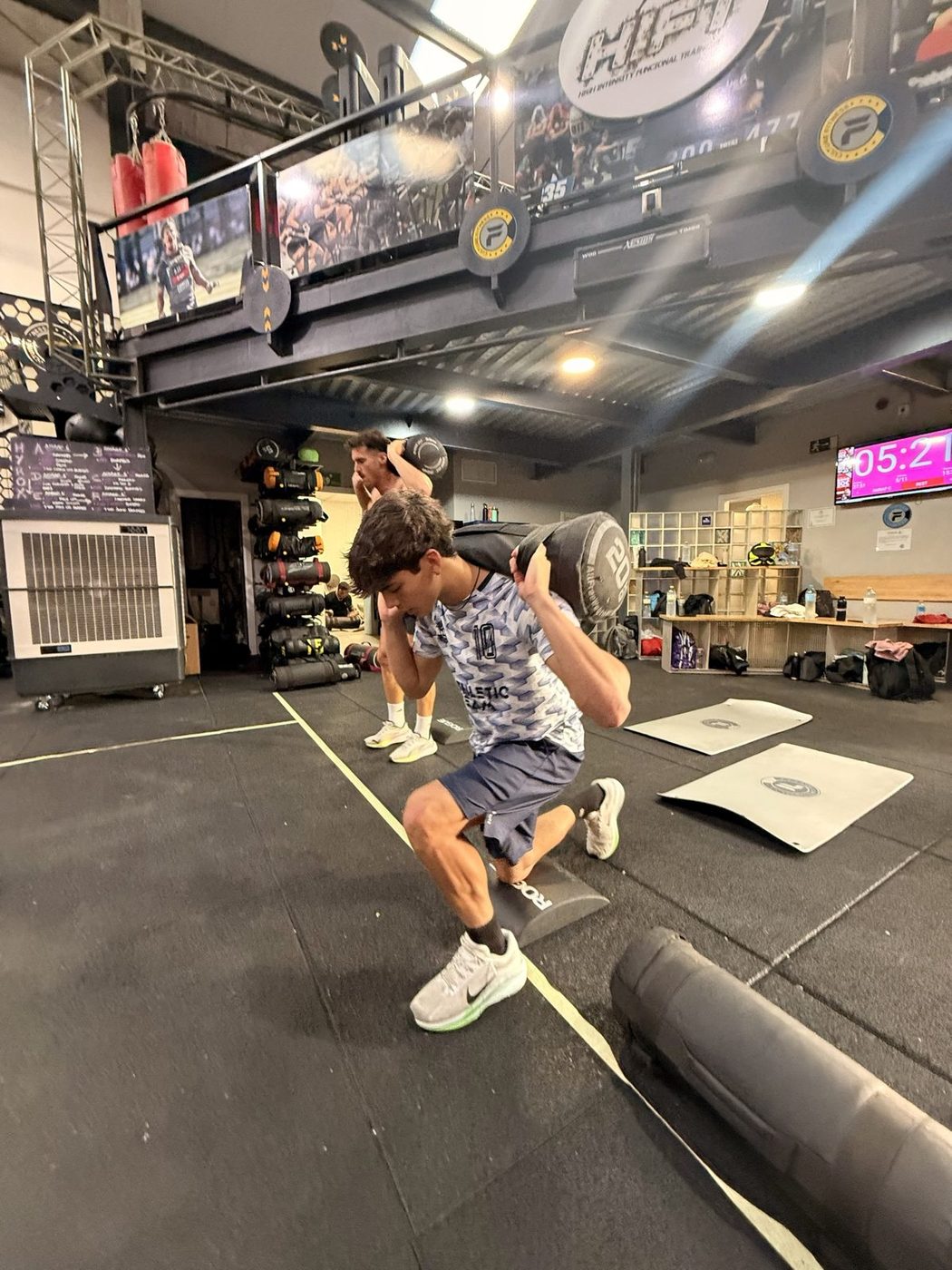Josh doing weighted lunges with a sandbag across his shoulders during a conditioning session.