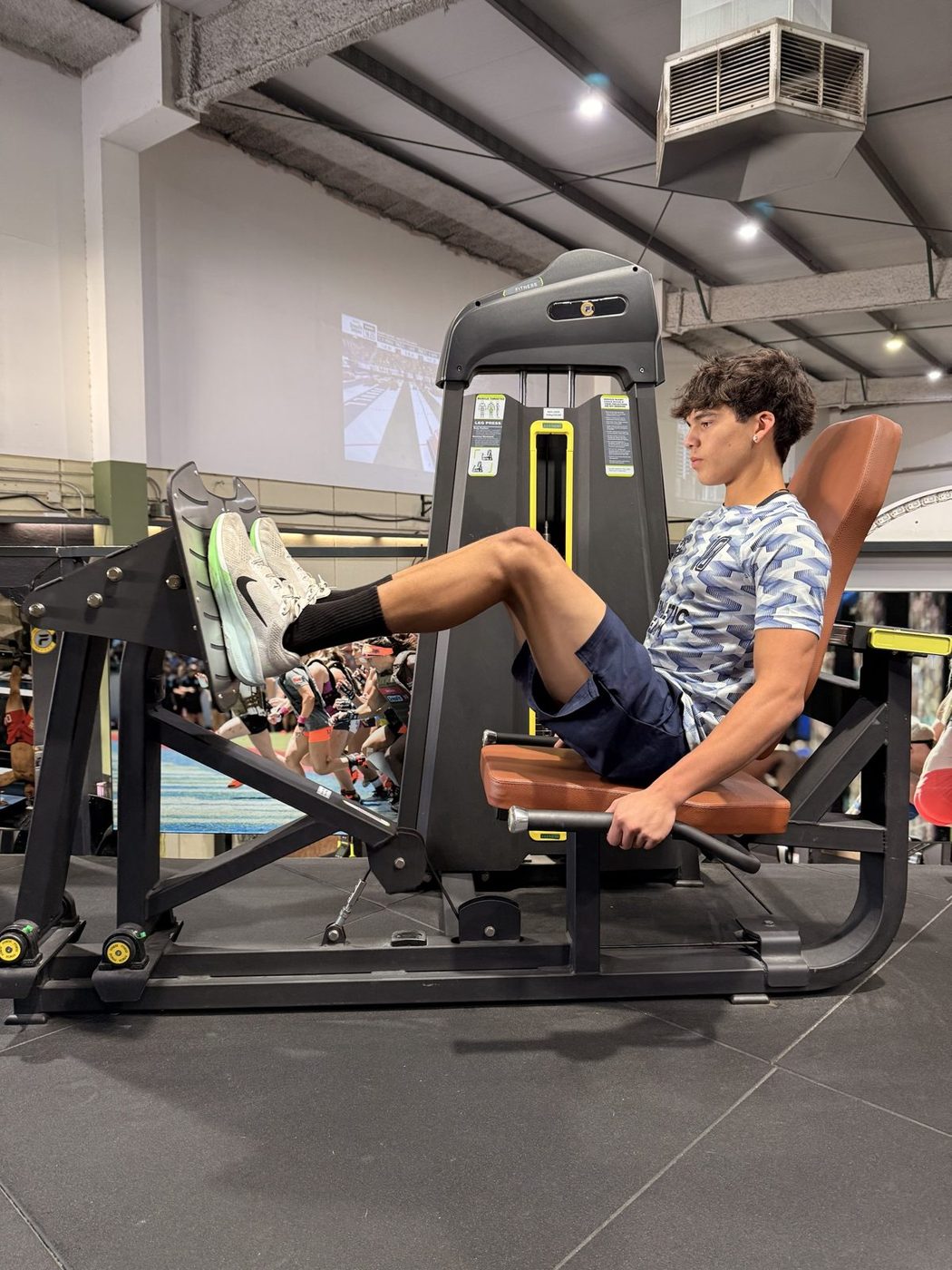 Josh on a seated leg press machine in the gym.
