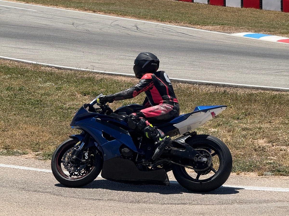 Josh in black and pink leathers on his blue R6, riding along the edge of the track past red and white kerbs.