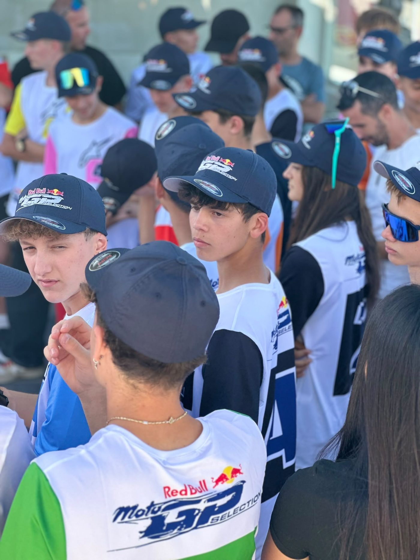 Josh, in a navy Red Bull MotoGP Selection cap, looks across a crowd of riders in matching caps and bibs at the selection event.