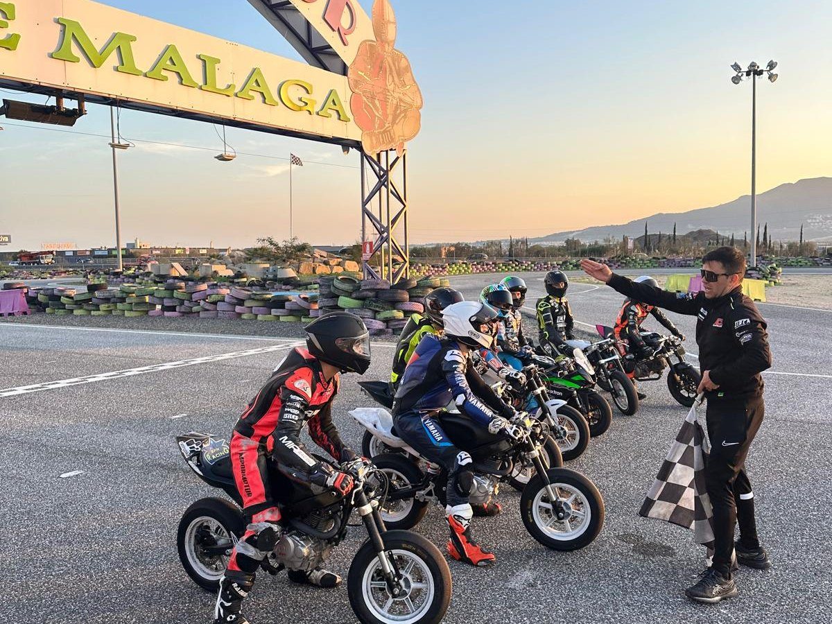 Josh on the start line in Málaga with other riders as a coach holds the chequered flag at sunset.