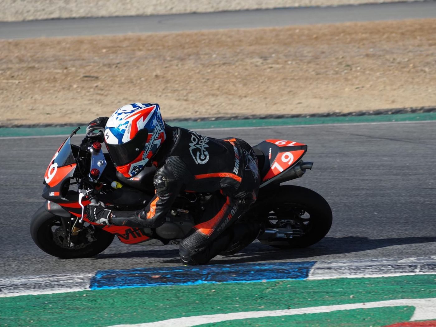Josh leaning through a corner on the orange and black MIR bike, number 19, with his knee close to the track.