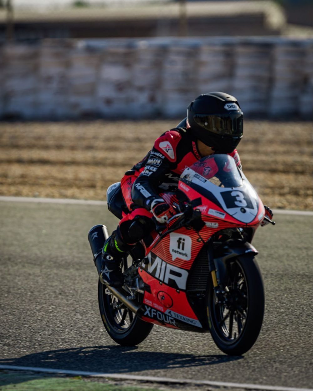 Josh on the red MIR bike on track in low sun.