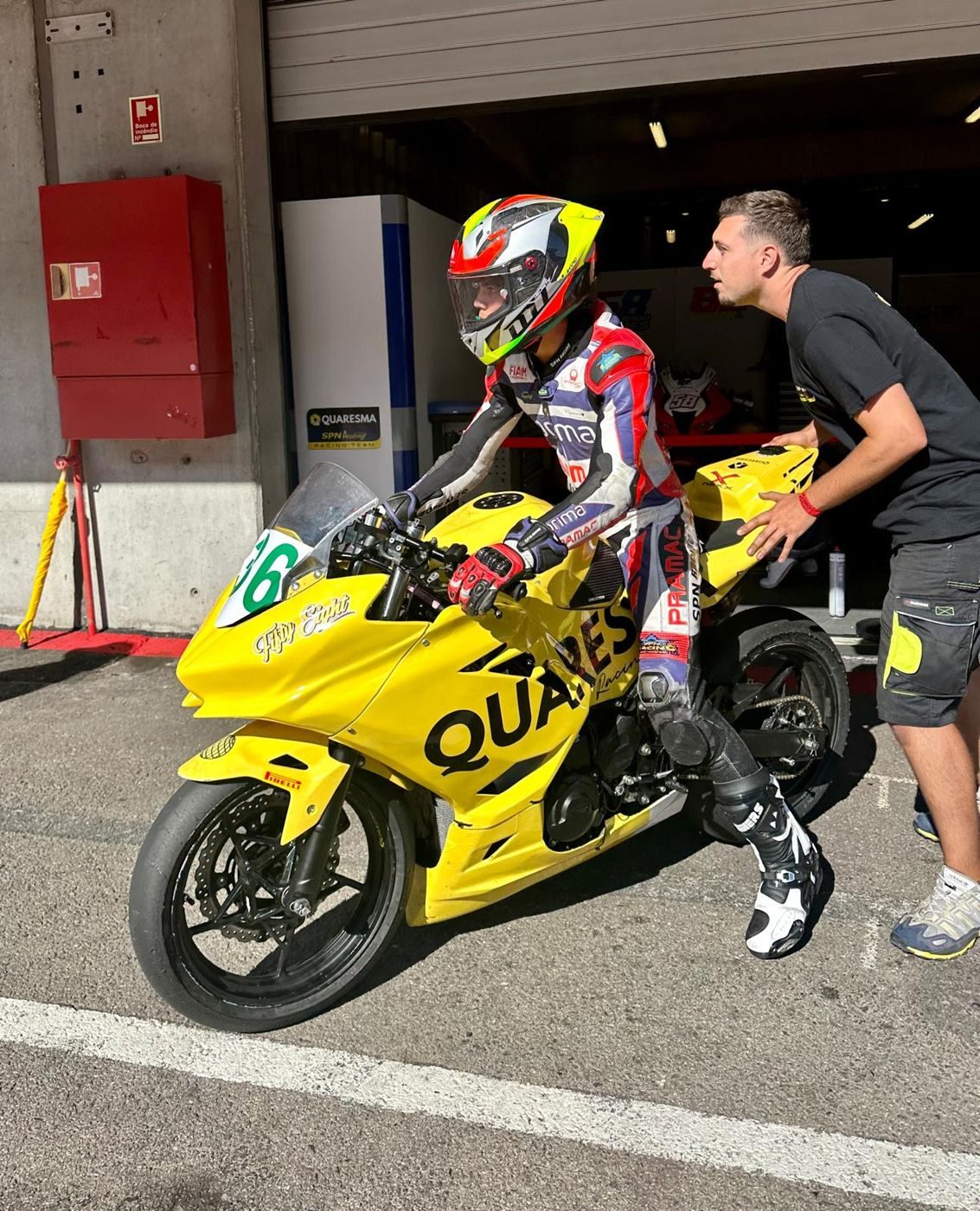 Josh in Pramac leathers leaving the pit garage on the yellow Quaresma bike, number 36, with a team member pushing the tail.