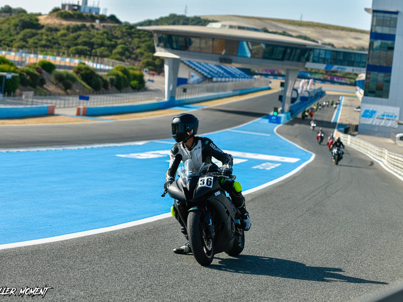 Josh on his black R6, number 36, riding down the pit lane in white and black leathers, with other riders following behind.